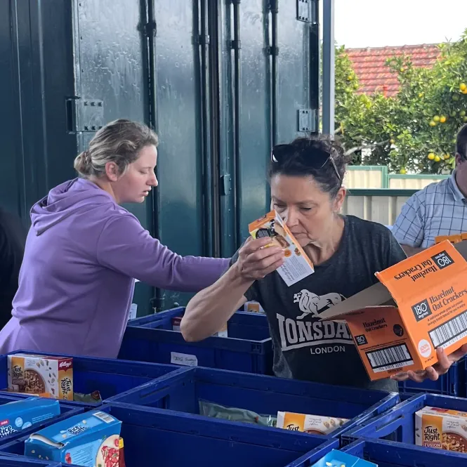 Two volunteers sorting boxes of food into crates